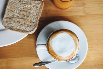Morning Hot Cappuccino Coffee with Toasted Whole Wheat Bread and Orange Juice, on wooden table