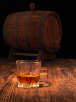 Glass of whiskey and vintage wooden barrel