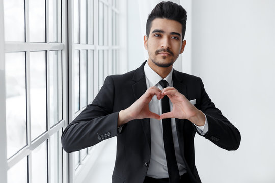 Young businessman in love shows heart sign