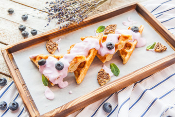 Fototapeta na wymiar Viennese waffles with honey and fresh berries blueberry and mint on black surface. Delicious dessert. Copy space