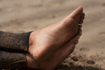 man feet, surfer with wetsuite sitting on the beach waiting for the waves