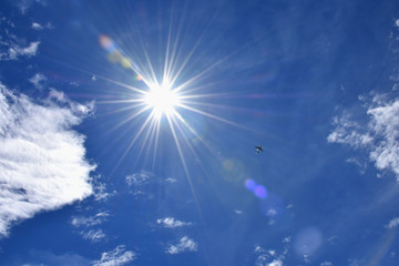 強い太陽の光を受け輝く航空機・青空と雲「空想・雲のモンスターたち（左右のモンスターはとけてしまったイメージ）」未来を導く、未来を創る、輝く未来、猛暑、高温注意、熱中症、紫外線、挑戦、夢、可能性などのイメージ