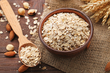 Oat flakes in bowl and spoon on wooden table