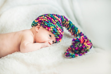 newborn baby in New Year's gnome Cap lays On a white blanket