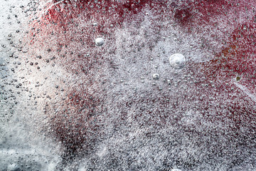Winter ice and snow with bubbles abstract background with red paint work behind