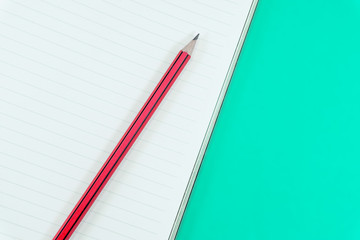 Notebook with pencil on green background
