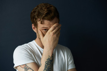 Masculinity concept. Headshot of handsome tattooed young European male fashion model dressed in...