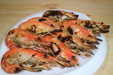 Flaming Grilled Whole River Prawns on White Plate Served on Wooden Table, with Selective Focus