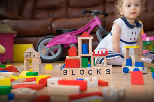 Two-year old  girl playing with wooden blocks.