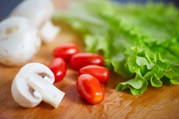 Fresh and tasty tomatoes, salad, champignon on wooden cutting board