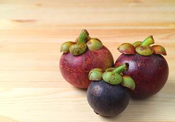 Three Different Size and  Color Ripe Purple Mangosteen Fruits on the Wooden Table, with Free Space for Design and Text  