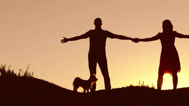 Couple in love dancing silhouette at sunset and kissing. Loving man and woman with dog dancing silhouette slow motion video