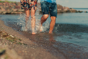 Feet of a loving couple running along the beach