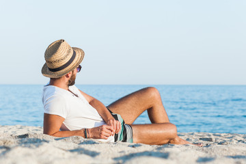 Young hipster man lying on the beach