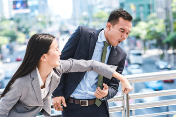 Angry Asian businesswoman punching colleague businessman in face outdoor