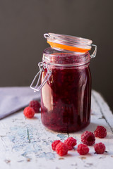 Homemade jam with raspberry on the wooden table.