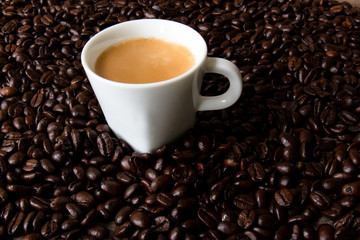 Full espresso cup surrounded by coffee beans