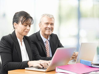 Obraz premium Business team at work. Shot of an senior investment advisor businessman and his female financial assistant analyzing financial data while working on laptops. 