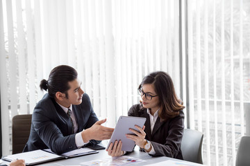 Fototapeta premium Young woman showing her co-workers his tablet computer as her explains something to them during a meeting or presentation
