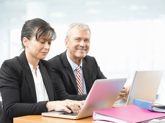 Business team at work. Shot of an senior investment advisor businessman and his female financial assistant analyzing financial data while working on laptops. 