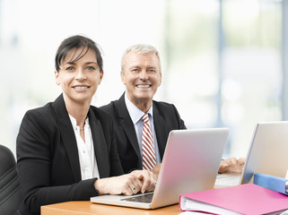 Business team at work. Shot of an senior investment advisor businessman and his female financial assistant analyzing financial data while working on laptops. 