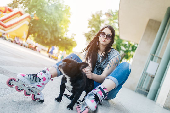 Urban portrait of beautiful and attractive girl with  French bulldog and sunglasses. Warm summer colors and haze. Strong back light.