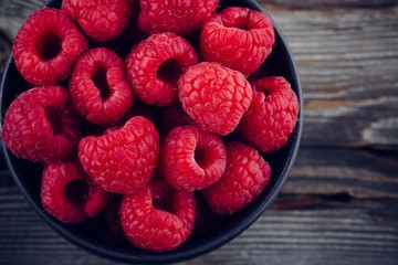Fresh ripe organic raspberry in a mug on a wooden background