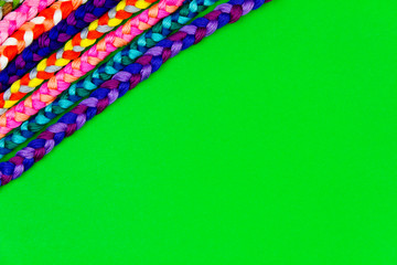 Colorful green background of pink, violet, yellow, green, red, purple knitted pigtail. Knitted concept. Embroidery workplace