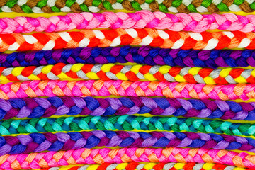 Background / pattern of colorful knitted pigtails from threads. Embroidery concept