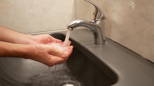 A man is washing his face with tap water.