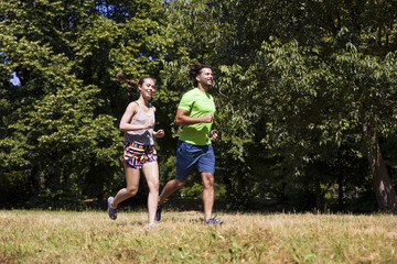 Fototapeta premium Young couple running in the park on a sunny day