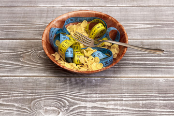 Macaroni from a meter with cornflakes in a wooden plate on the background of a wooden table.