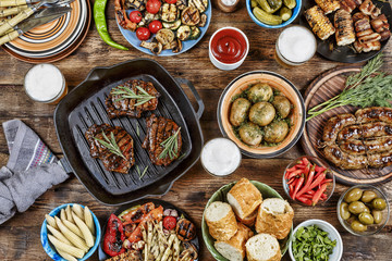 Outdoors Food Concept. Appetizing barbecued steak, sausages and grilled vegetables on a wooden picnic table with copy space, top view © hannamartysheva