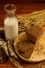 Still life with a glass jug of milk, rye bread, ears of corn