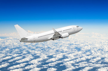 White airplane flies high in the sky above the clouds blue sky