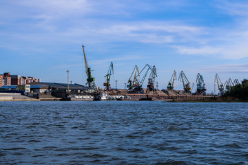 Cranes in a river port ship goods to ships. Frame made from boat