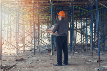 Engineer with blueprint in building construction site