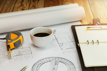 Cup of coffee with measurement tool and blueprint, architectural concept
