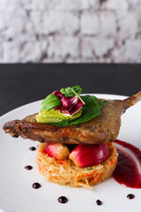Restaurant meals. Duck confit with vegetables on black background