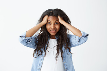 Beautiful Afro-american woman in casual clothes with long wavy hair looking nervously holding her...