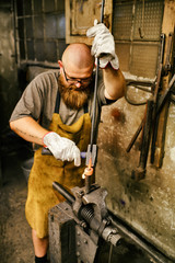 Blacksmith with beard working in his workshop