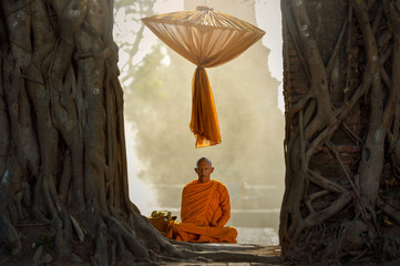 Buddhist monks are sitting samati on temple in mist sunset,Thailand - obrazy, fototapety, plakaty