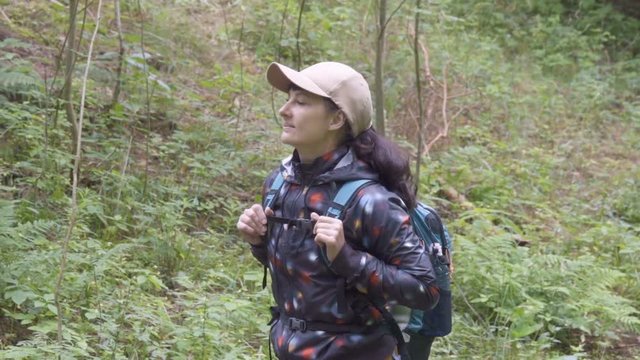 Young Woman travels through forest. Female tourist with a backpack walk through a forest road. Hiking outdoors on nature. Enjoying Nature at Camping.