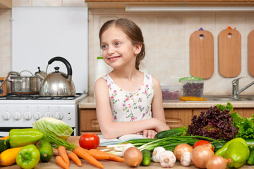 child girl with fruits and vegetables in home kitchen interior, read cooking book, healthy food concept