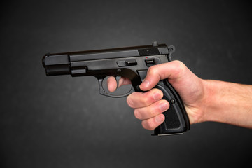 Gun in hand over black background 
