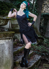 Young beautiful pin up glamour girl with green color hair, high boots on old stone vintage stairs