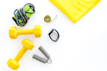 Fitness for loosing weight. Dumbbells, jump rope and measure tape on white background top view copyspace