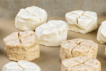 unbaked bread rolls on backing paper