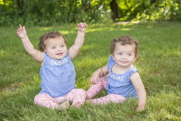 Identical twin girls sitting in the park
