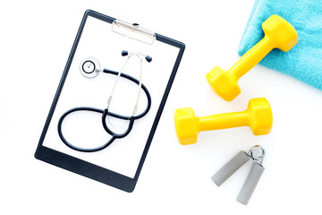 Sport and health. Fitness. Dumbbells and stethoscope on white background top view
